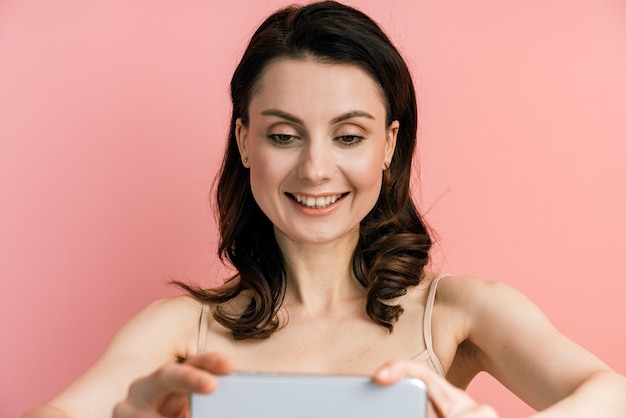 Foto di carino, positivo, giovane donna in posa prendendo un selfie con la fotocamera.