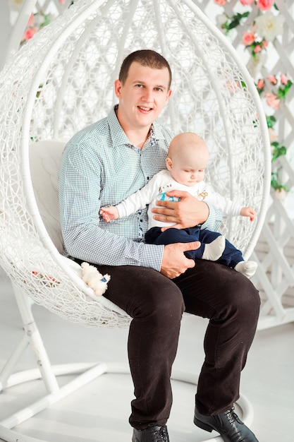 Photo of dad and son are sitting in a round fashionable chair