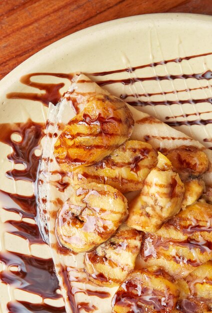 Photo of a delicious crepe with banana and decorated with liquid chocolate