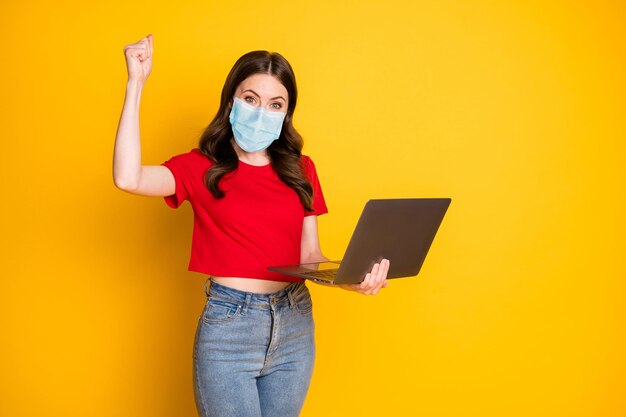 Photo of delighted girl work laptop win raise fists wear respiratory red t-shirt isolated bright shine color background