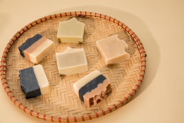 Photo of different hand made soap bars on bamboo tray isolated on beige background