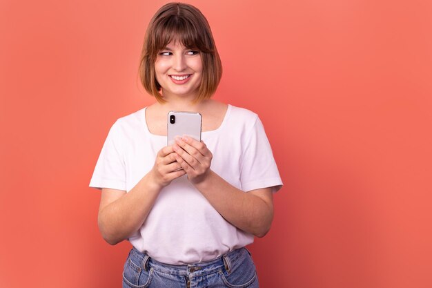 ピンク色の背景に夢のような陽気なかわいい女の子の外観スタンド空のスペースホールド電話の写真