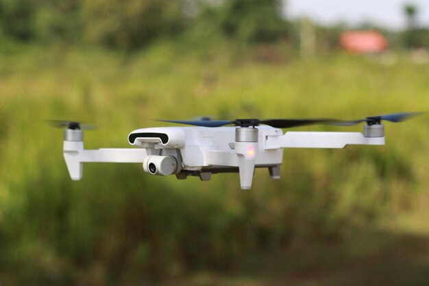 Photo a photo of a drone flying with a blurry propeller against a green open space background technology photo concept