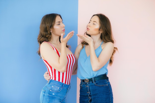 Фотография эмоциональных двух подруг, стоящих изолированно на цветном фоне