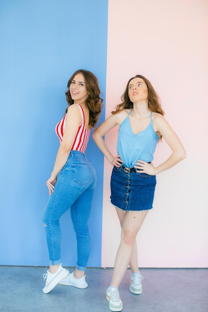 Photo of emotional two women friends standing isolated over color background