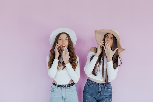 Photo of emotional two women friends standing isolated over purple background.