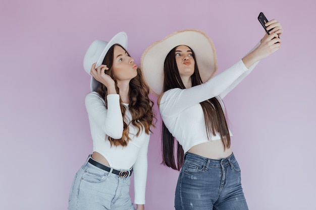 Photo of emotional two women friends standing isolated over purple background.