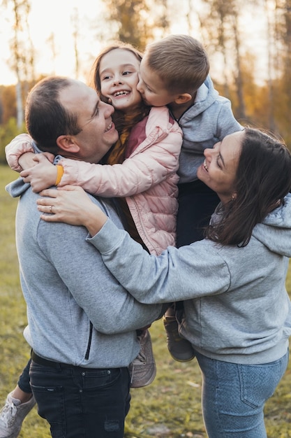 photo of a family standing together in the park posing while looking at each other happy people