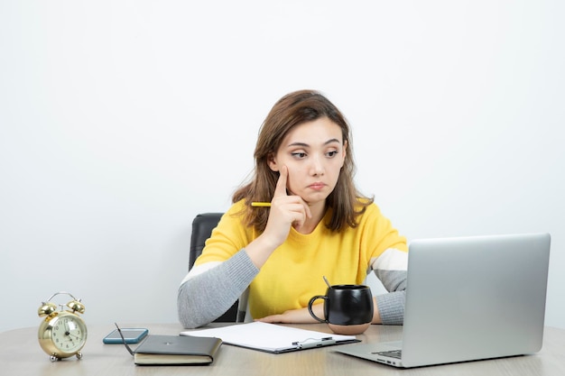 Photo of female office worker sitting at the desk with laptop . High quality photo
