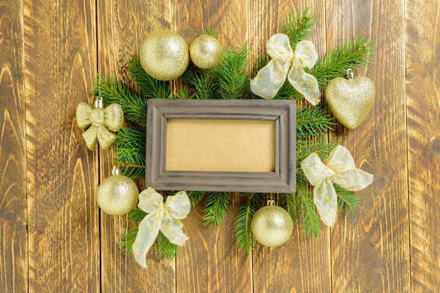 Photo photo frame between christmas decoration, with golden color balls and ribbons on a brown wooden table. top view, frame to copy space.