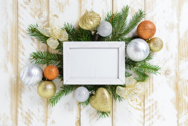 Photo frame between Christmas decoration, with orange and white balls on a white wooden table. Top view, frame to copy space.