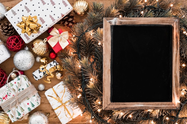 Photo frame on fir twigs between fairy lights near Christmas decorations