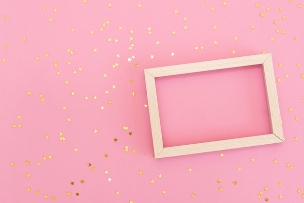 Photo frame mock up with space for text, golden sequins confetti on pink background.