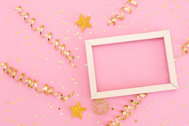 Photo frame mock up with space for text, golden sequins confetti on pink background. 