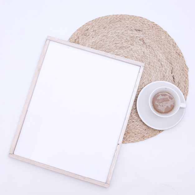 Photo frame mockup and cup of coffee on white background. Flat lay, top view, copy space.