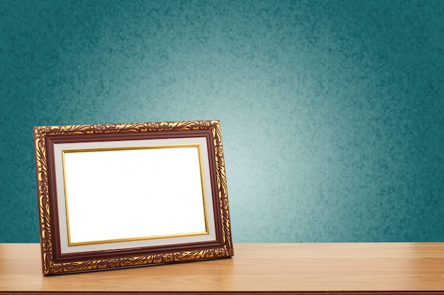 Photo frame on wooden table over green wall background