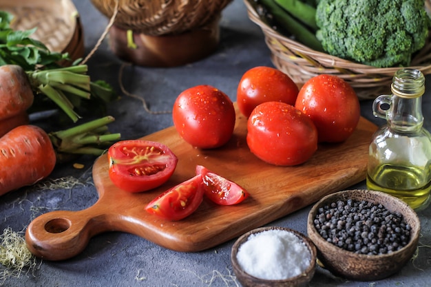 야채, 당근, 소금, 후추, 옥수수, 브로콜리 주위 커팅 보드에 신선한 토마토의 사진. 토마토 슬라이스. 토마토 수확. 나무 테이블.