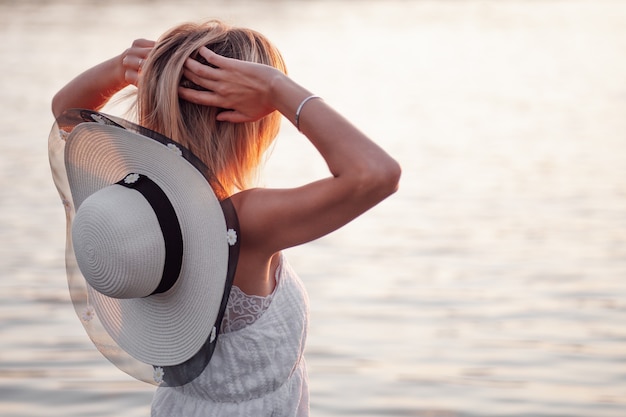 Foto dalla schiena di una bionda sullo sfondo di un fiume una bella giovane donna felice sta...