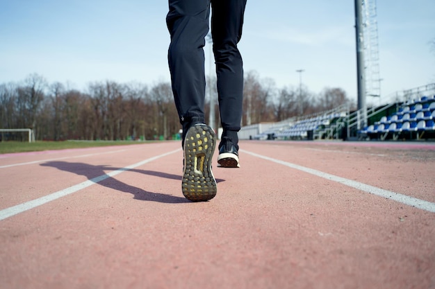 Photo from back of legs of athlete running through stadium