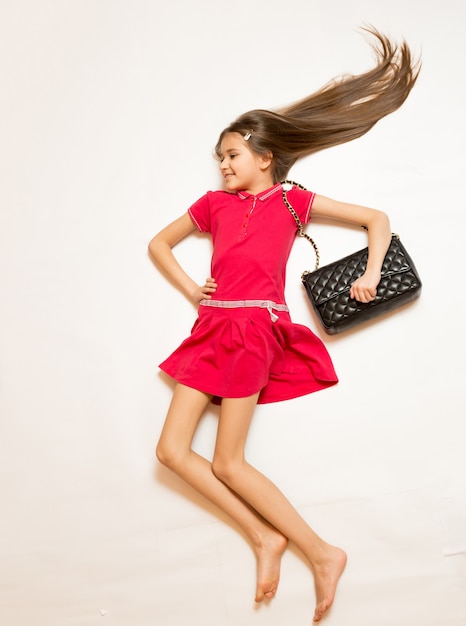 Photo from top of fashionable girl with long hair lying on white floor