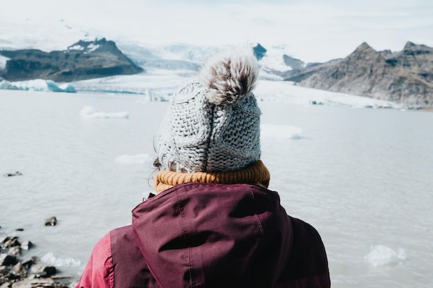 アイスランドの氷河の前にいる女性の後ろからの写真冬旅行の寒さの概念