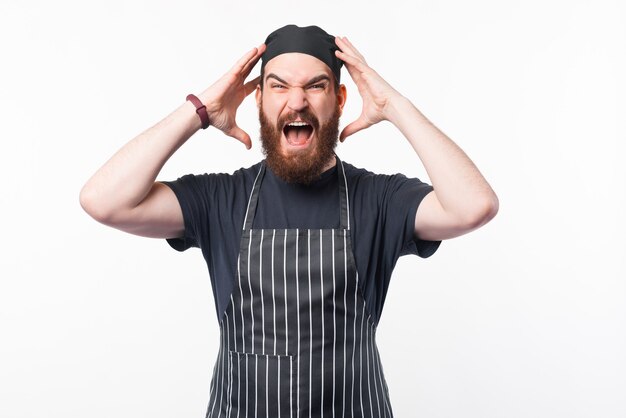 Photo of frustrated bearded chef looking at the camera over white