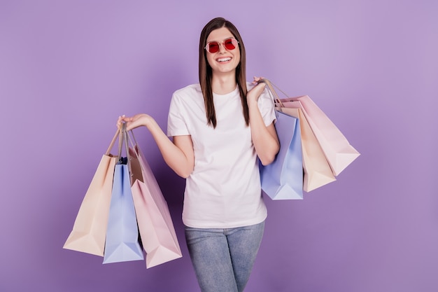 Photo of funny positive lady carry shopping packs isolated violet background