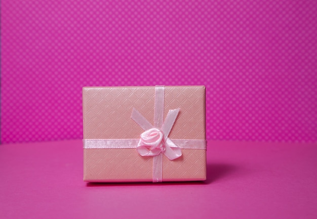 Photo of a gift box with a bow under different points of view on a pink background front view