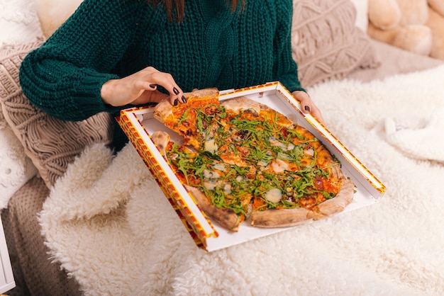 Photo of a girl hand taking a slice of pizza.