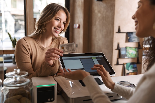 Photo photo of girl happy excited buyer in cafe standing near administrator holding debit card