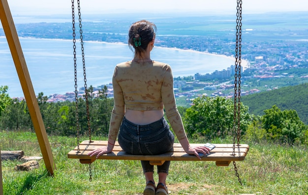 Photo of a girl sitting on a swing in the mountains