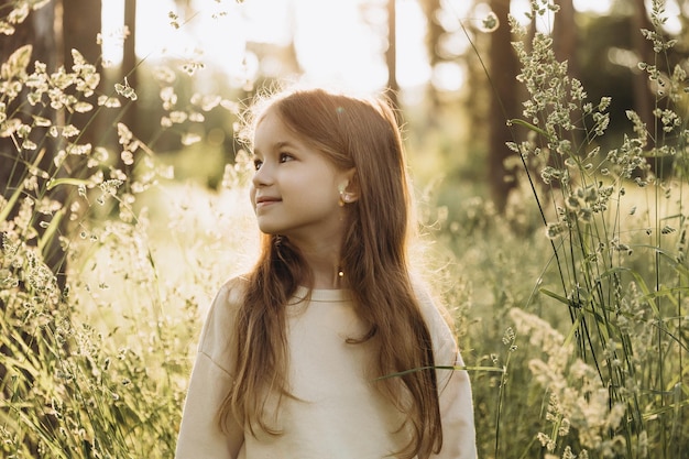 最後の暖かい夏の日に背の高い草のある公園を歩いている女の子の写真