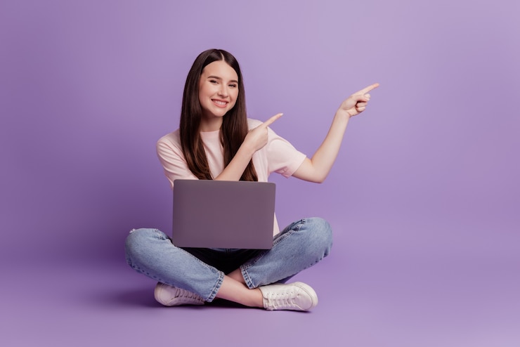Photo photo of girl with laptop direct fingers empty space on purple background