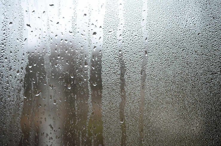 Photo a photo of the glass surface of the window, covered with a multitude of droplets of various sizes. background texture of a dense layer of condensate on glass