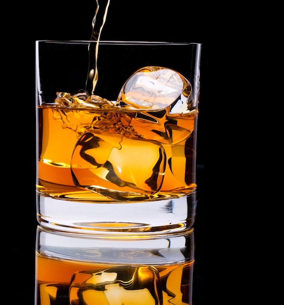 Photo of a glass of whiskey and ice on a black background