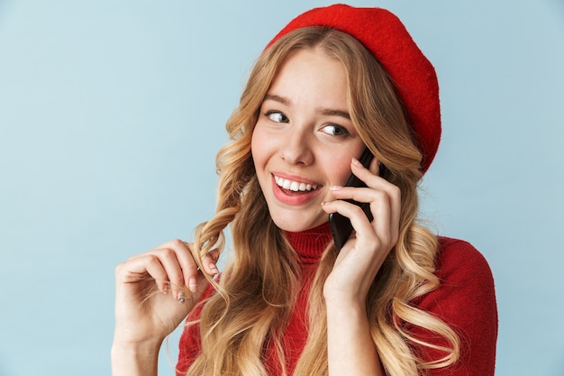 分離された携帯電話で話している赤いベレー帽を身に着けているゴージャスな女の子20代の写真