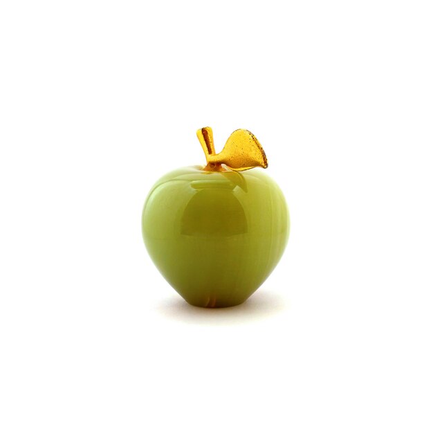 Photo of green onyx apple with gold leaves isolated on a white background