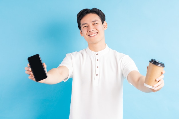携帯電話と紙コップを手に持っているハンサムなアジア人男性の写真
