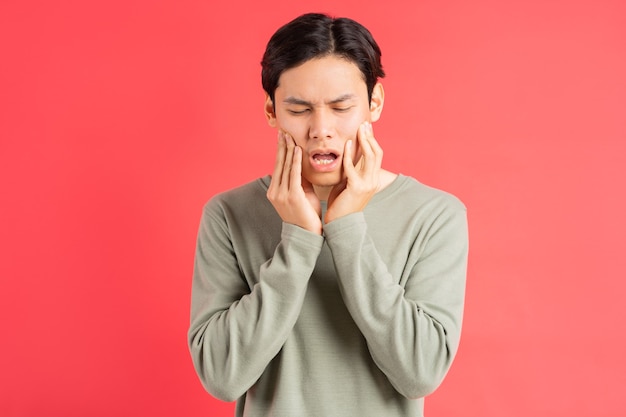 A photo of a handsome Asian man suffering from tooth decay