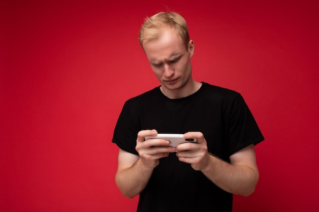 Photo of handsome concentrated upset dissatisfied young blonde man isolated over red background wall