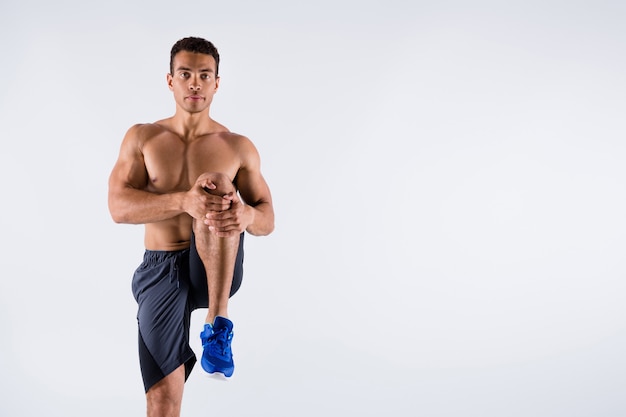 Photo of handsome macho sportsman dark skin guy doing warm up exercise focused stretch leg muscles