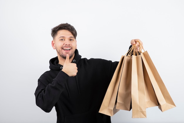 Photo of handsome man in black hoodie carrying bunch of craft bags