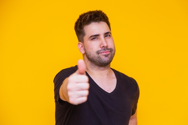 Photo of handsome man in casual t-shirt smiling on camera with thumb up