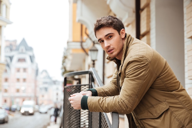 Photo of handsome young man walking on the street and looking at camera.