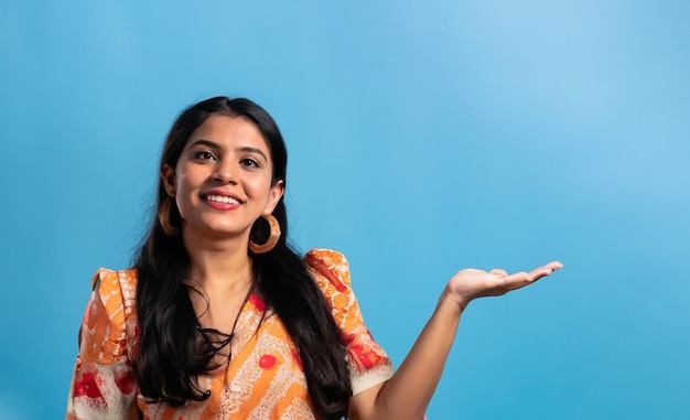 Photo happy asian woman dressed in summer clothes smiling with open hand gesture on blue background