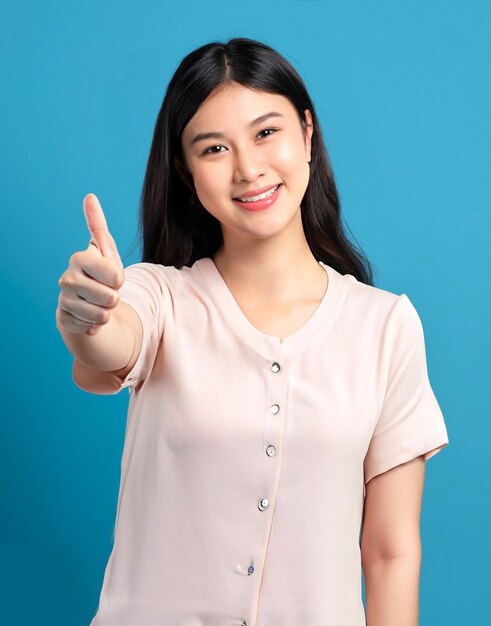 photo happy beautiful korean girl showing thumbs up in approval smiling blue background