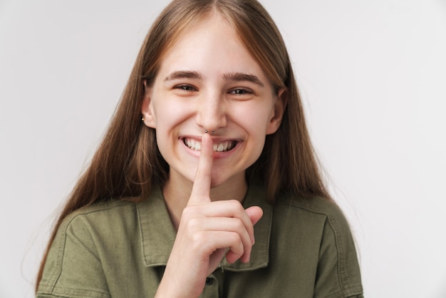 Photo of happy caucasian woman making silence gesture and smiling 