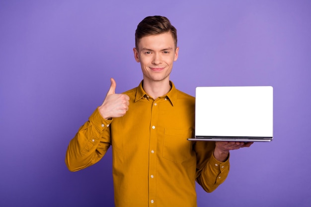 Photo of happy cheerful man showing screen laptop computer looking make thumb up symbol choice isolated vivid background