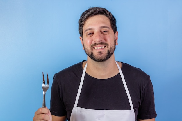 Photo of happy chef man holding utensil for cooking meat
