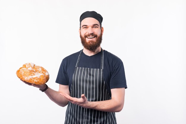 焼きたてのパンを提示する幸せなシェフの男の写真